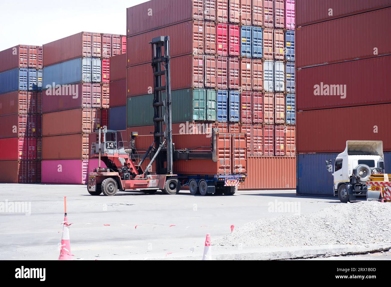 Carrello elevatore a forche e contenitori impilati nel porto. Foto Stock