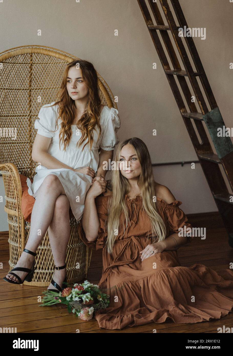 Modelli rossi e biondi in ambientazione bohémien, che tengono le mani in abiti. Foto Stock