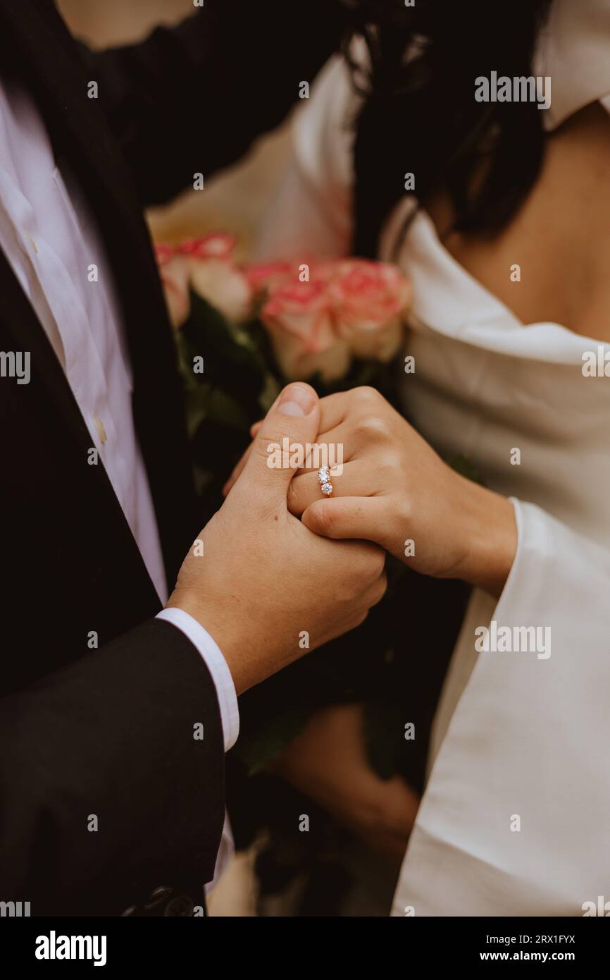 Primo piano della coppia fidanzata con anello diamantato e bouquet. Foto Stock