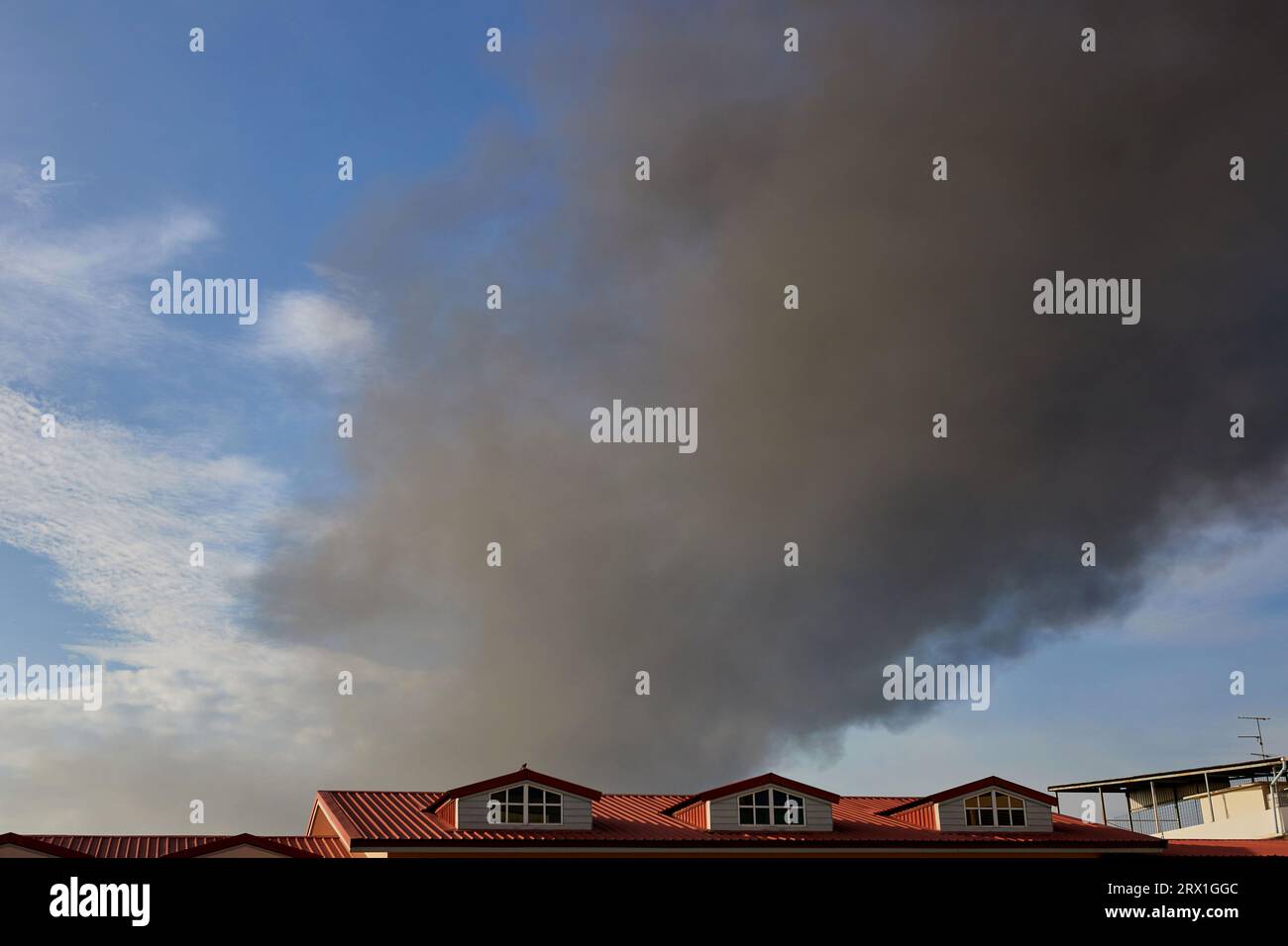 Un fumo spesso ricopre parte del cielo sul tetto Foto Stock