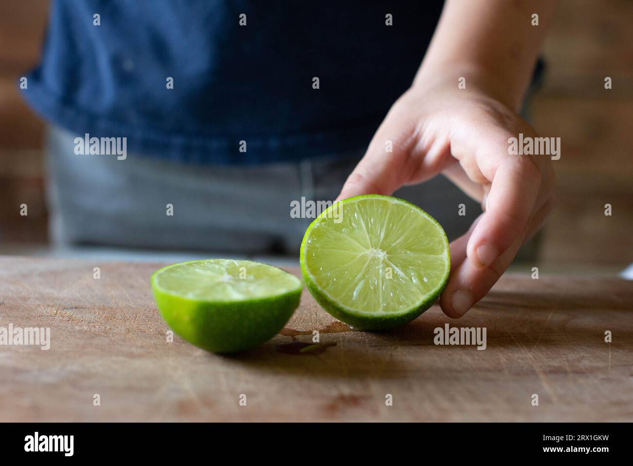 Lime tagliata a fette da ragazzo in camicia blu Foto Stock
