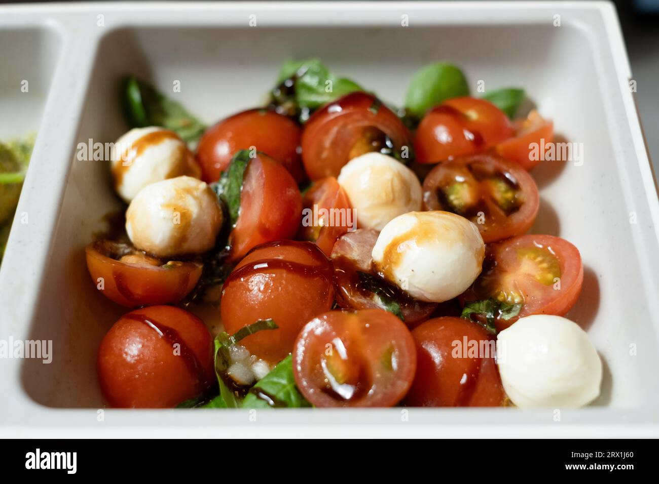 Fotografia di un'insalata di pomodoro ciliegia e mozzarella con foglie di basilico e filo di aceto balsamico, parte del pranzo presso il ristorante Mini Chef della LEGO House, Bi Foto Stock
