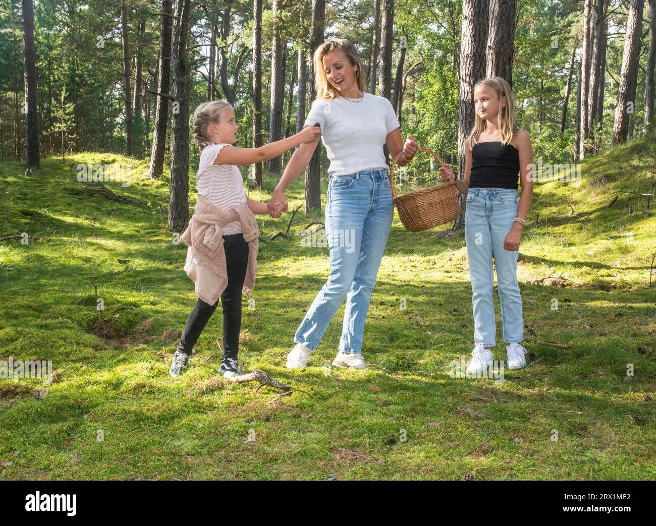 Donna bionda con due ragazze, 7 e 10 anni, alla ricerca di funghi nella foresta di Ystad, Scania, Svezia, Scandinavia Foto Stock