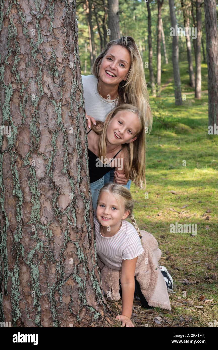 Donna bionda con due ragazze, 7 e 10 anni, che si diverte nella foresta di Ystad, Scania, Svezia, Scandinavia Foto Stock