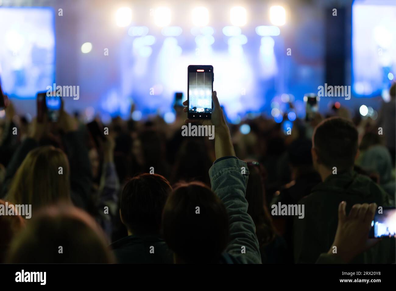 Mani che utilizzano il telefono con fotocamera per scattare foto e video durante un concerto dal vivo, lo smartphone registra festival di musica dal vivo, scatta foto sul palco del concerto anteriore, Happy Foto Stock