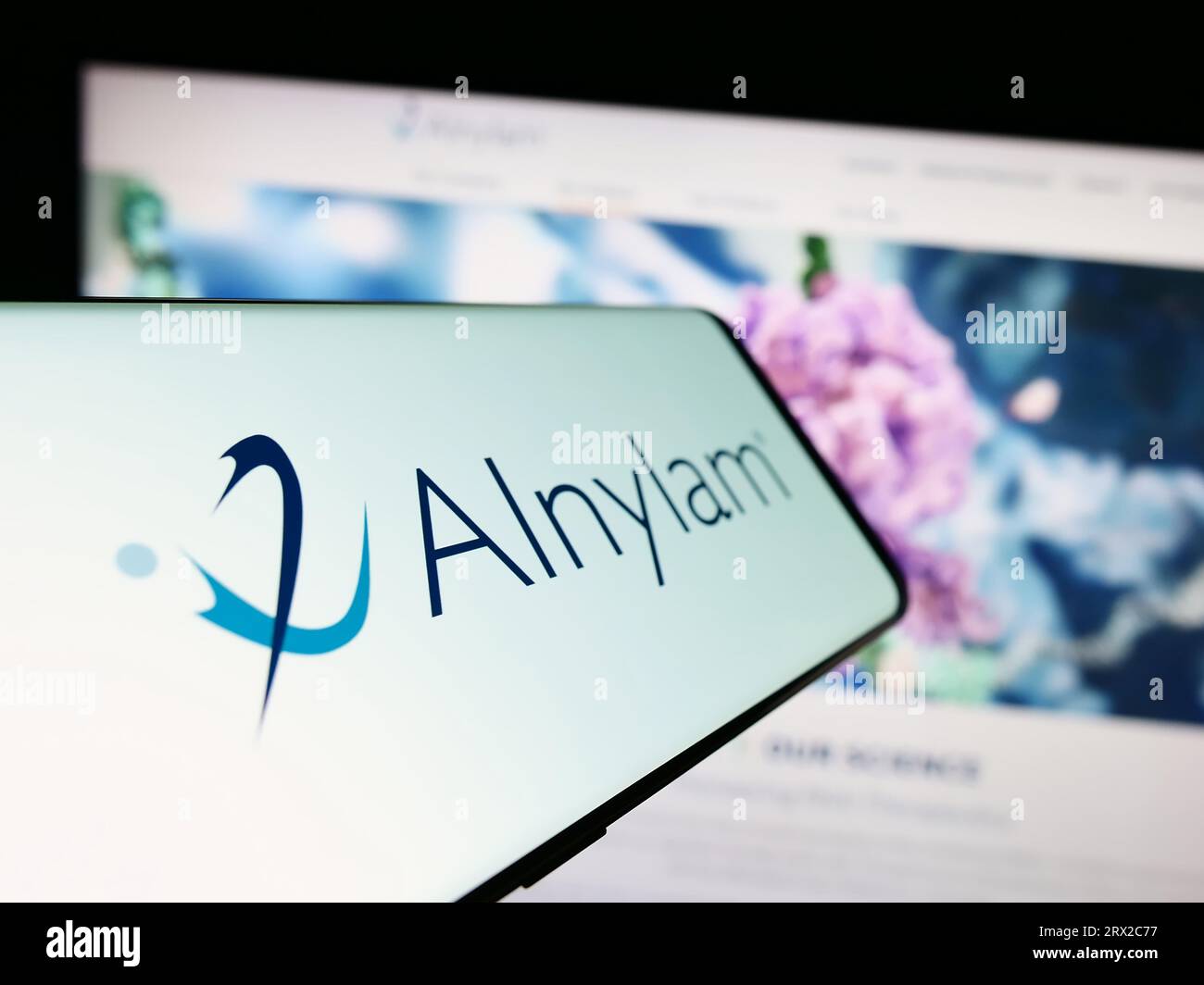 Telefono cellulare con logo della società americana Alnylam Pharmaceuticals Inc. Sullo schermo davanti al sito Web. Mettere a fuoco il display centrale sinistro del telefono. Foto Stock
