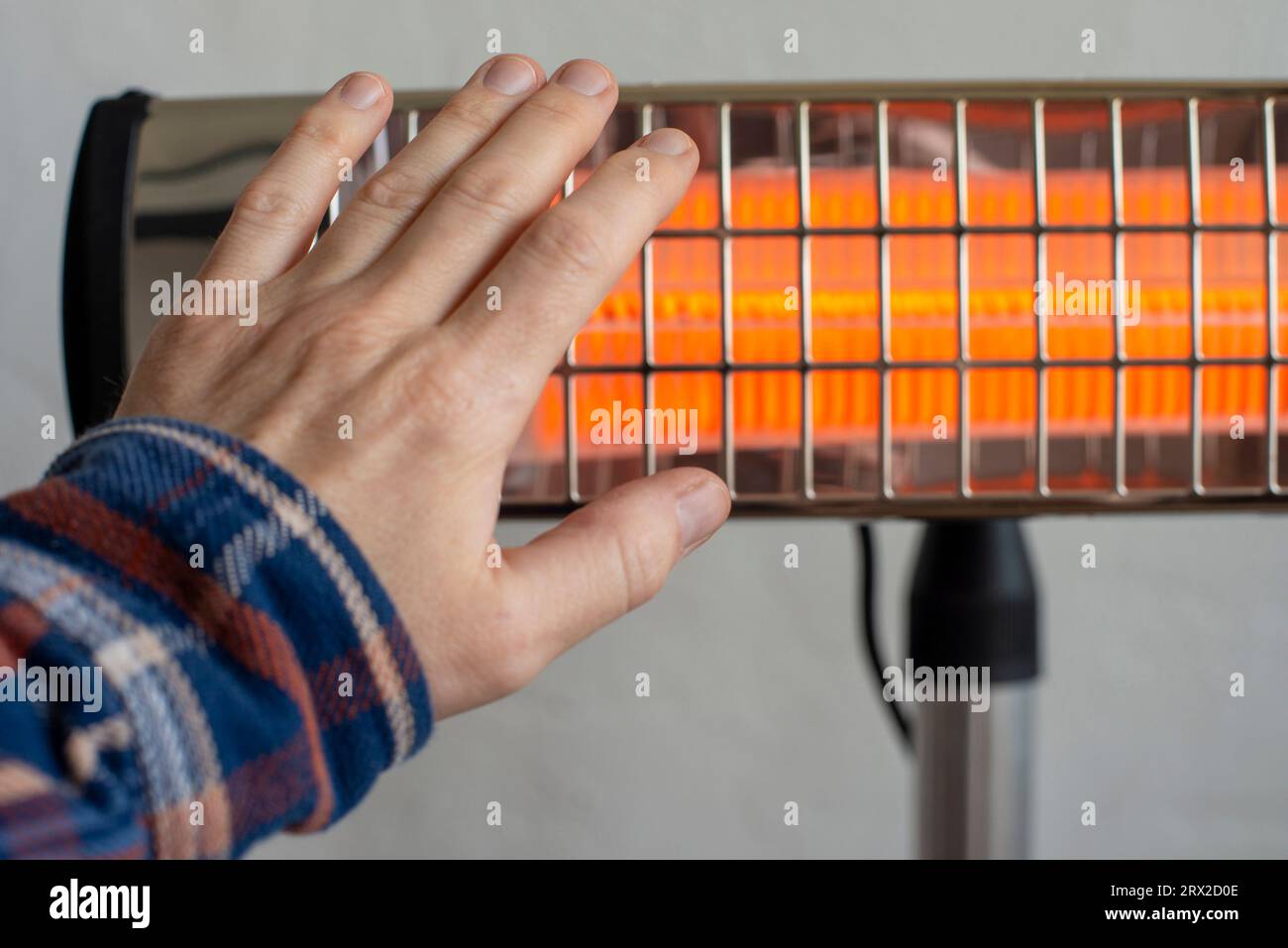 Maschio caucasico che riscalda la mano vicino al riscaldatore a infrarossi. Spazio per il testo Foto Stock