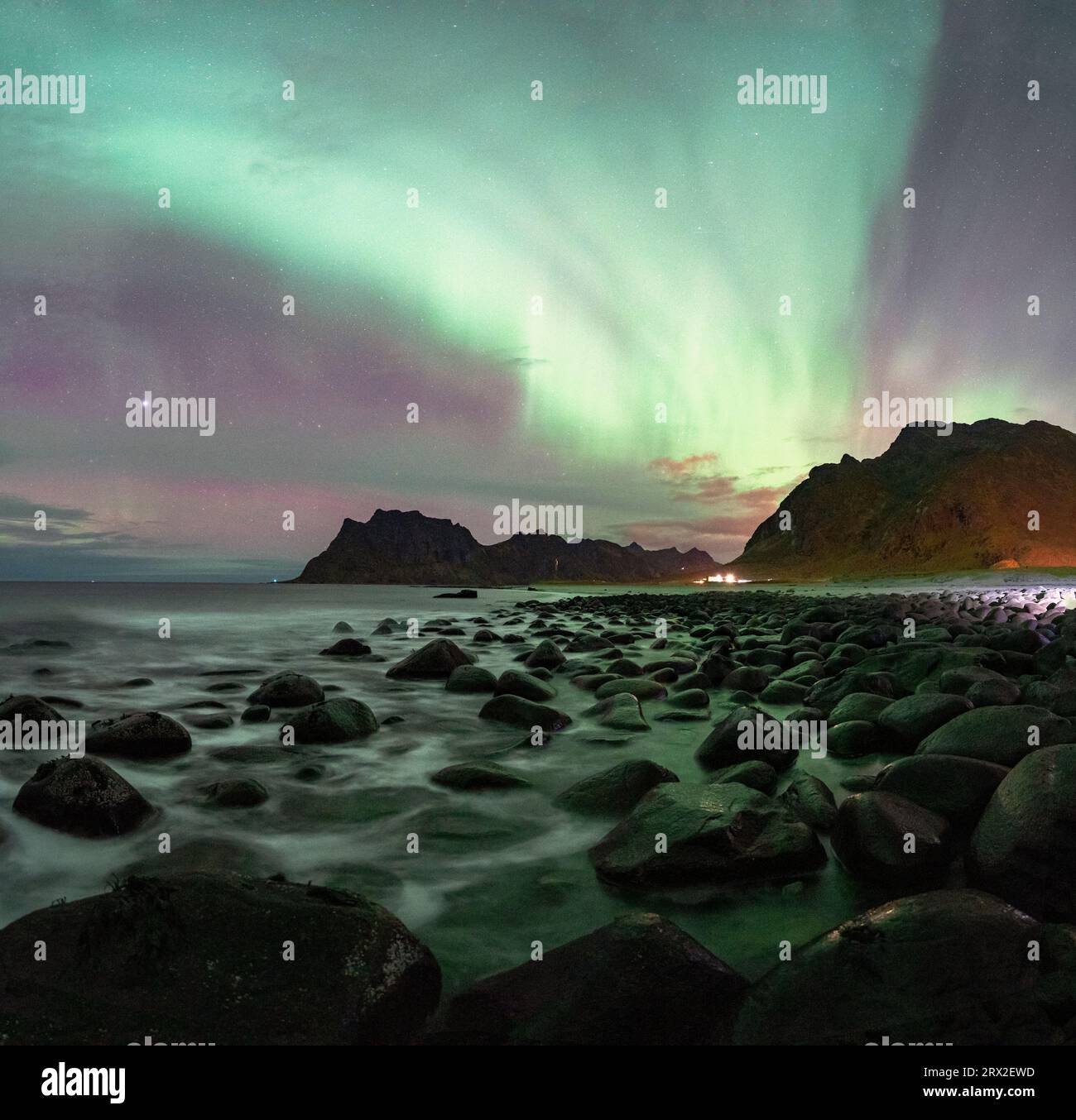 Onde che si infrangono sulle rocce della spiaggia di Uttakleiv sotto l'aurora boreale (aurora boreale), Vestvagoy, isole Lofoten, Nordland, Norvegia, Scandinavia Foto Stock