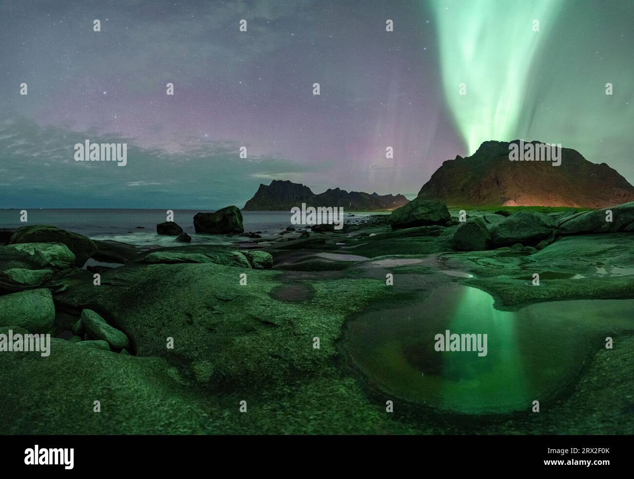 Le luci verdi dell'aurora boreale (aurora boreale) si accendono sulle montagne e sulla spiaggia di Uttakleiv, Vestvagoy, Isole Lofoten, Nordland, Norvegia Foto Stock