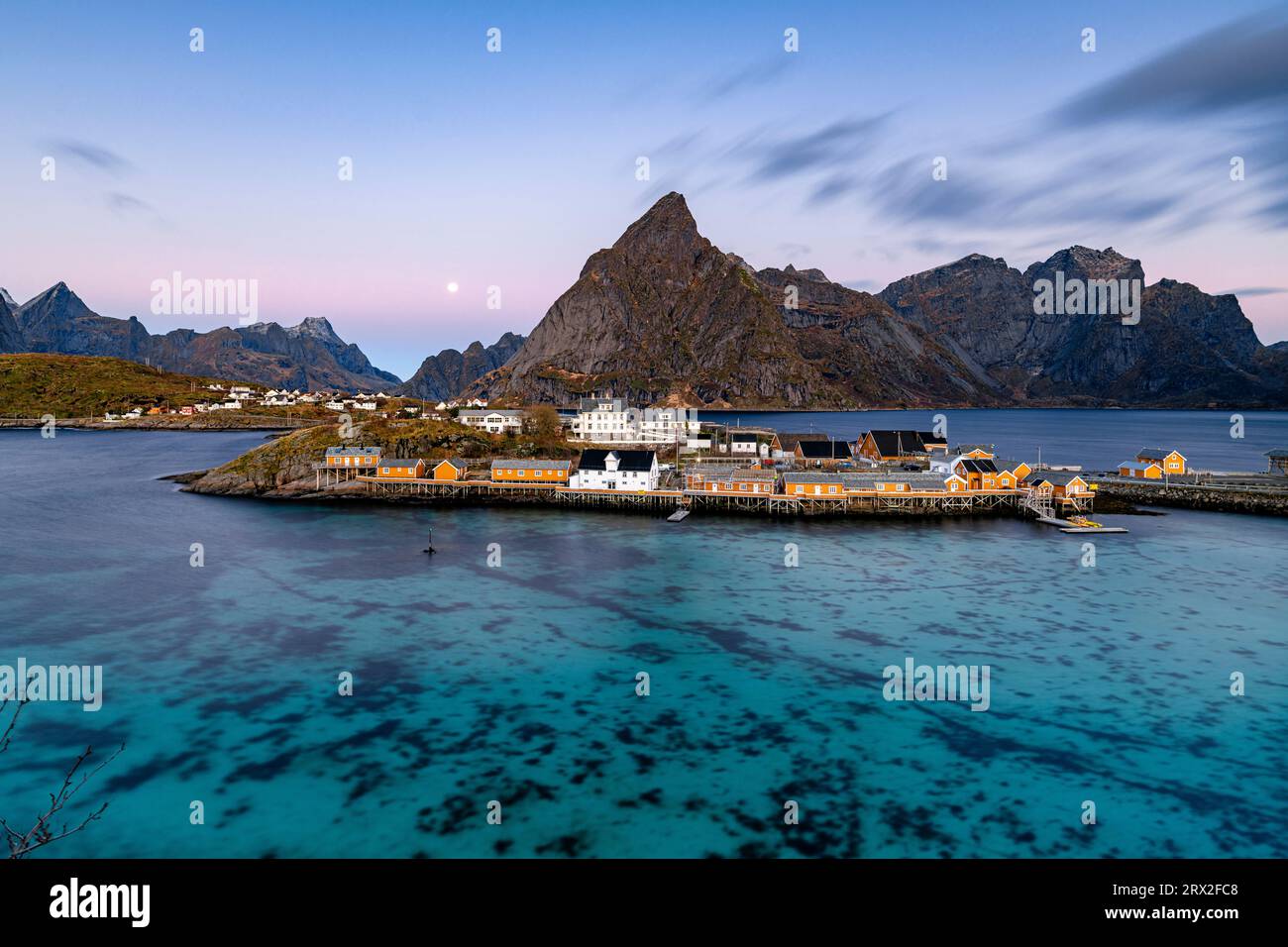 Alba sul monte Olstind e villaggio di pescatori di Sakrisoy, affacciato sul mare blu freddo, sulle isole Lofoten, sul Nordland, sulla Norvegia, sulla Scandinavia, Europa Foto Stock