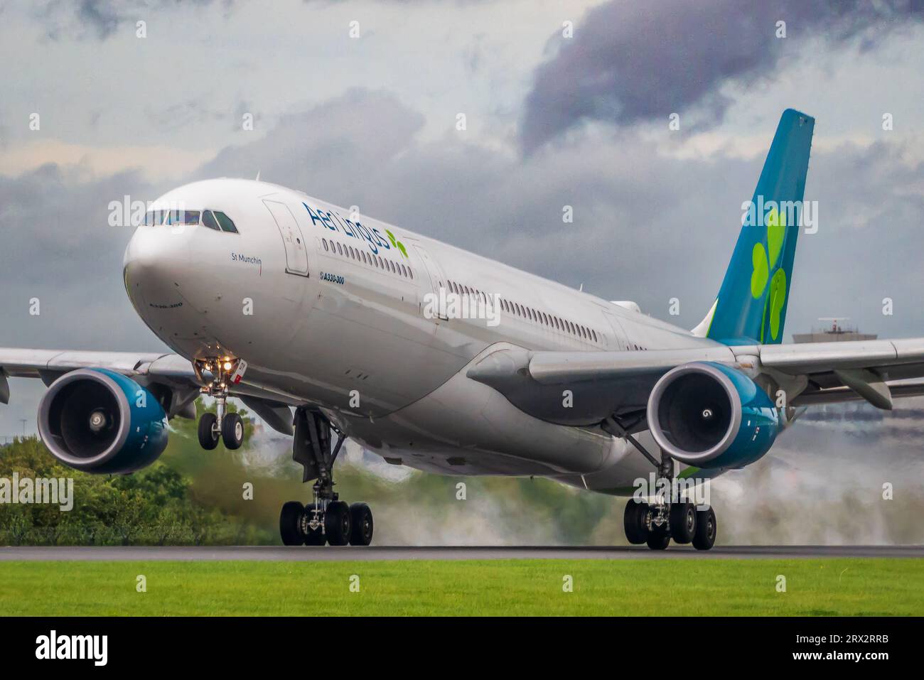 Aer Lingus Airbus A330-300 di nome St Munchin decolla dall'aeroporto di Manchester per la spinta del getto sulla pista bagnata. Foto Stock