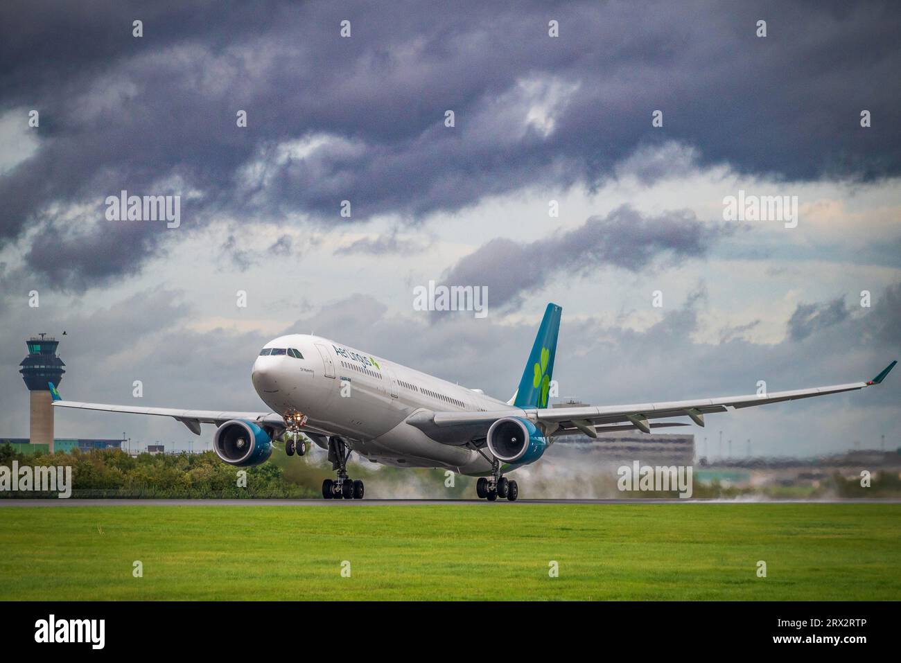 Aer Lingus Airbus A330-300 di nome St Munchin decolla dall'aeroporto di Manchester per la spinta del getto sulla pista bagnata. Foto Stock