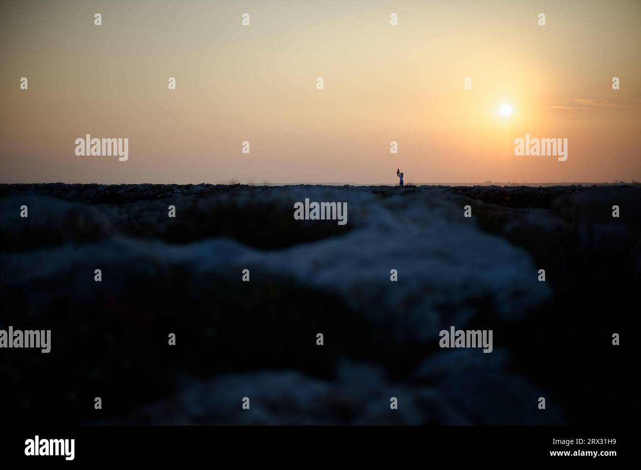 mamma che cresce suo figlio al tramonto Foto Stock