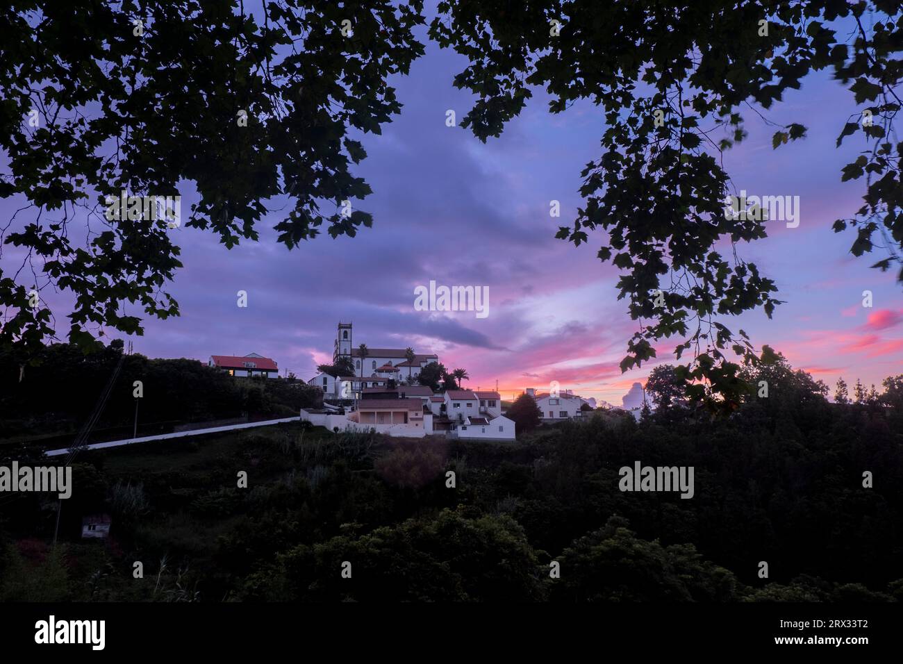 Colori del tramonto su Santo Antonio de Nordestinho incorniciato da rami d'alberi, isola di Sao Miguel, isole Azzorre, Portogallo, Atlantico, Europa Foto Stock