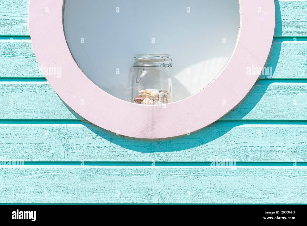 Vetro con conchiglie nella finestra rotonda di una capanna da bagno blu-verde nelle dune di sabbia sulla spiaggia di Skanör med Falsterbo, Skåne, Svezia Foto Stock