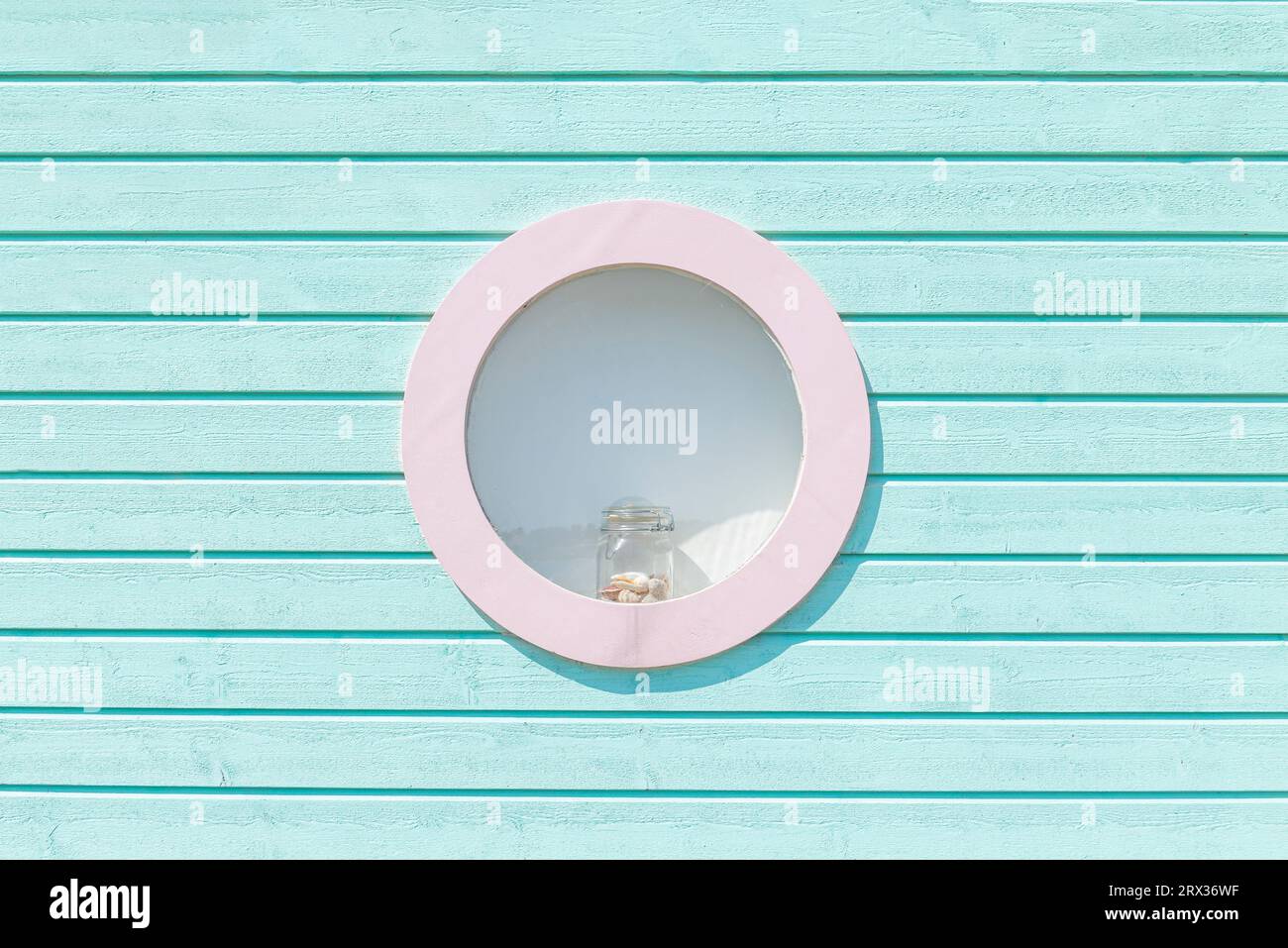 Vetro con conchiglie nella finestra rotonda di una capanna da bagno blu-verde nelle dune di sabbia sulla spiaggia di Skanör med Falsterbo, Skåne, Svezia Foto Stock