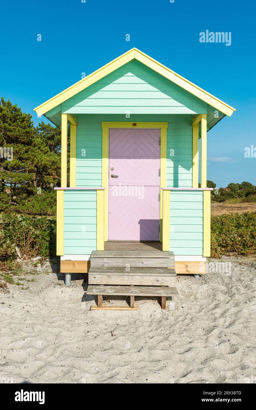 Vista frontale del fronte in legno di un rifugio balneare giallo blu-verde sulla spiaggia di Skanör med Falsterbo al Öresund al sole serale, Skåne, Swe Foto Stock
