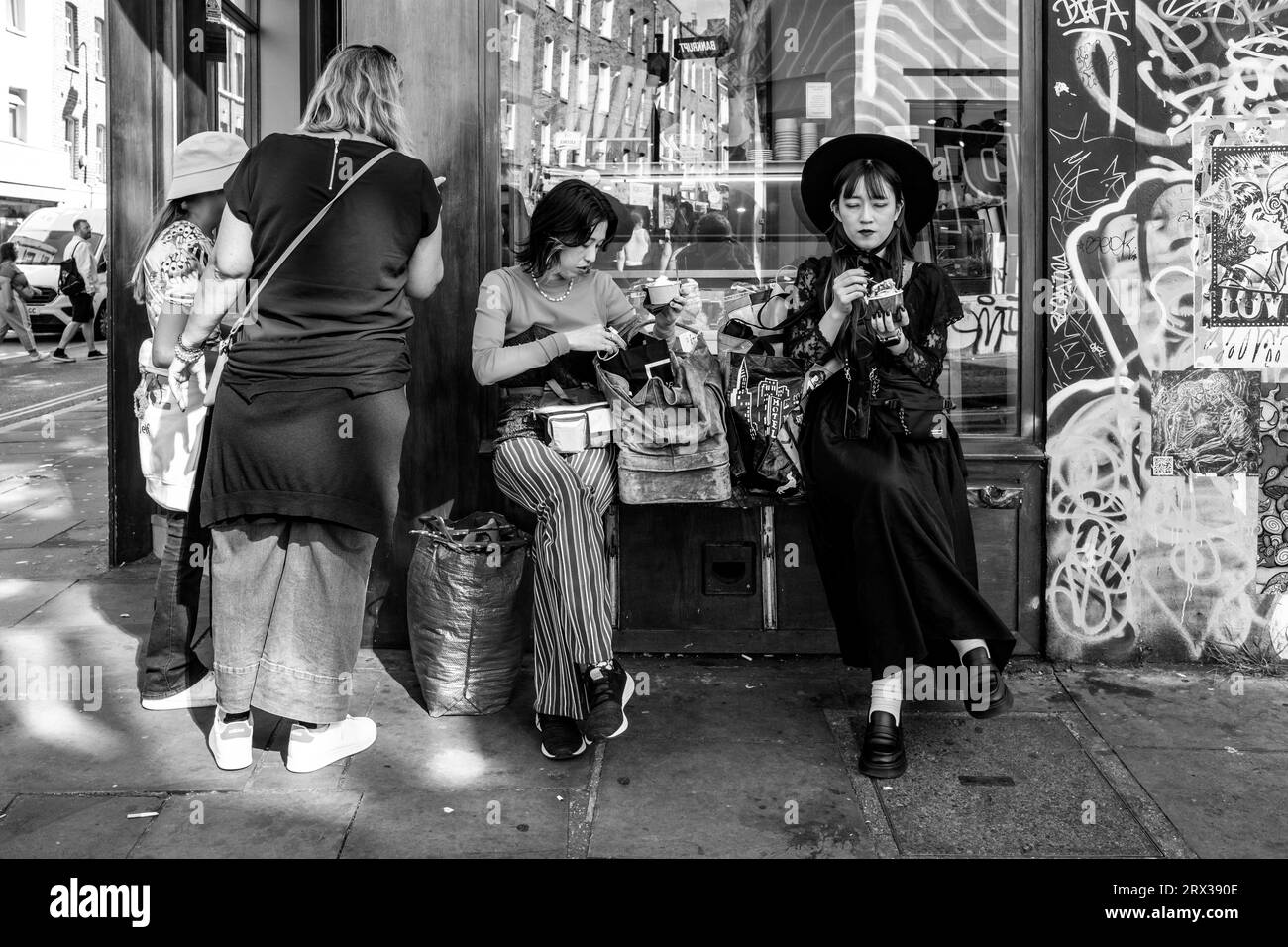 Turisti asiatici che mangiano gelato, Brick Lane, Londra, Regno Unito. Foto Stock