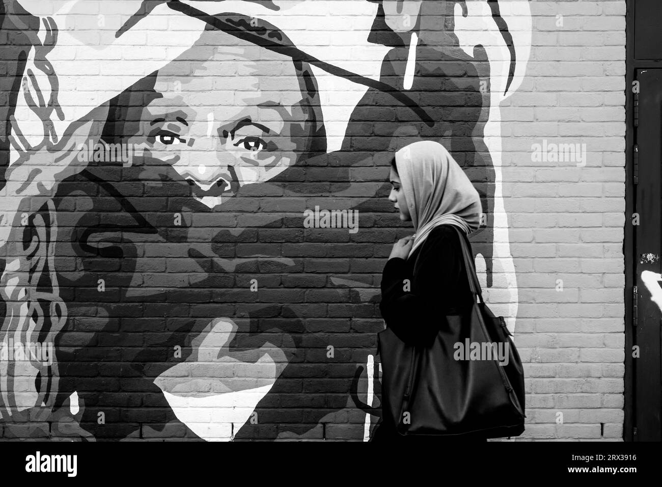 A Young Woman passeggia davanti a Colourful Street Art, Shoreditch, Londra, Regno Unito. Foto Stock