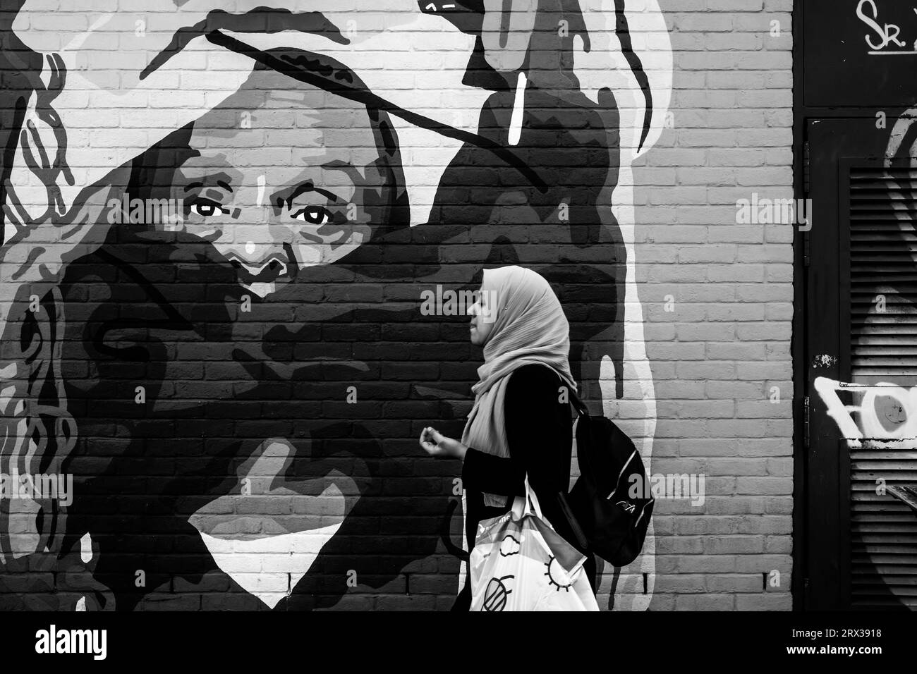 A Young Woman passeggia davanti a Colourful Street Art, Shoreditch, Londra, Regno Unito. Foto Stock