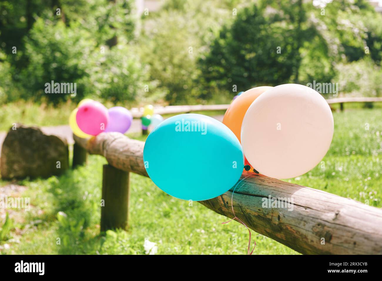 Molti palloncini colorati attaccati a una recinzione di legno, concetto di festa all'aperto Foto Stock