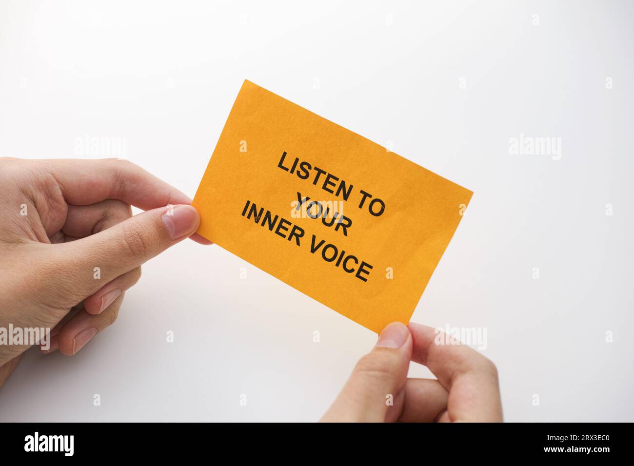 Un uomo che tiene una nota di carta gialla con la frase, ascolta la tua voce interiore nelle sue mani. Primo piano. Foto Stock