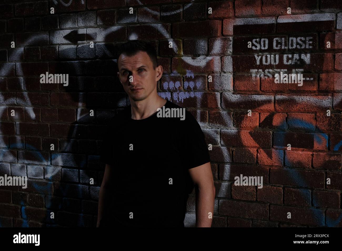 Street alleyway modello maschile con graffiti crepuscolari Foto Stock