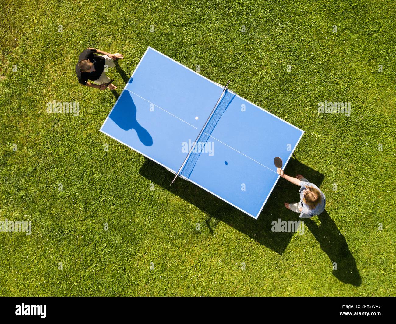 Vista aerea persone che giocano a ping pong all'aperto. Vista dall'alto due ragazzi che giocano a ping pong su un prato verde. Sport all'aperto con vista aerea Foto Stock
