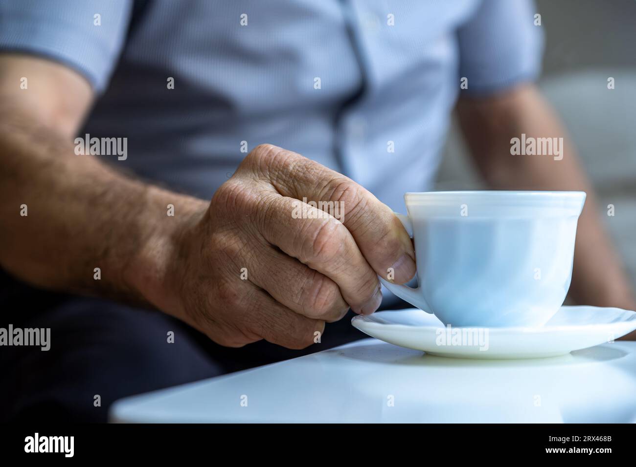 Il vecchio le mani reggono una tazza di caffè su camicie bianche Foto Stock