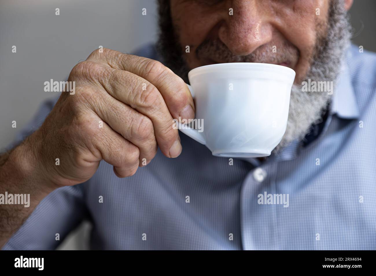 Vecchio che beve caffè con un sorriso in faccia Foto Stock
