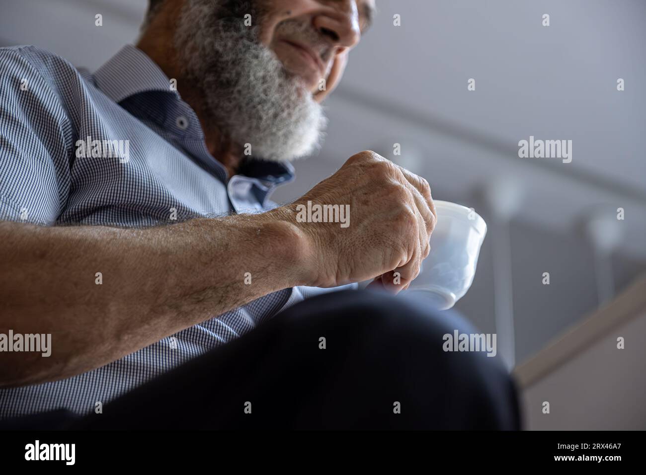 Vecchio che beve caffè con un sorriso in faccia Foto Stock