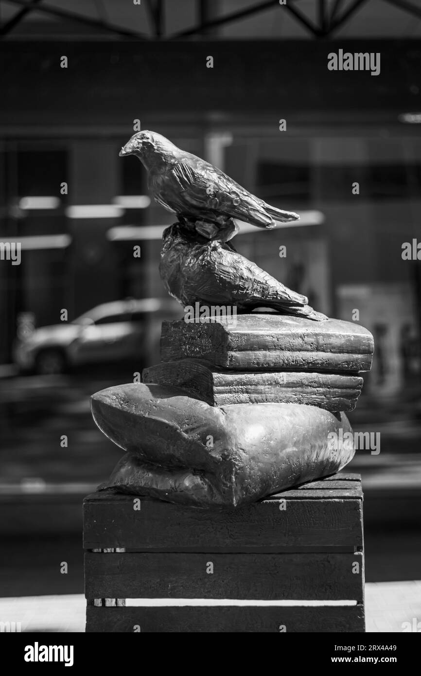 Immagine in bianco e nero di una scultura di un uccello arroccato su un libro e un cuscino su una cassa sul marciapiede nel centro di Portland, Oregon Foto Stock