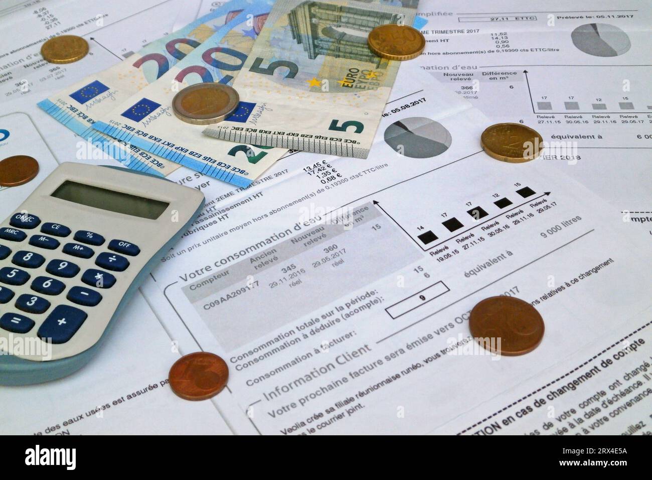 Un calcolatore e alcune monete e banconote in euro sulla sommità di una bolletta dell'acqua francese. Foto Stock
