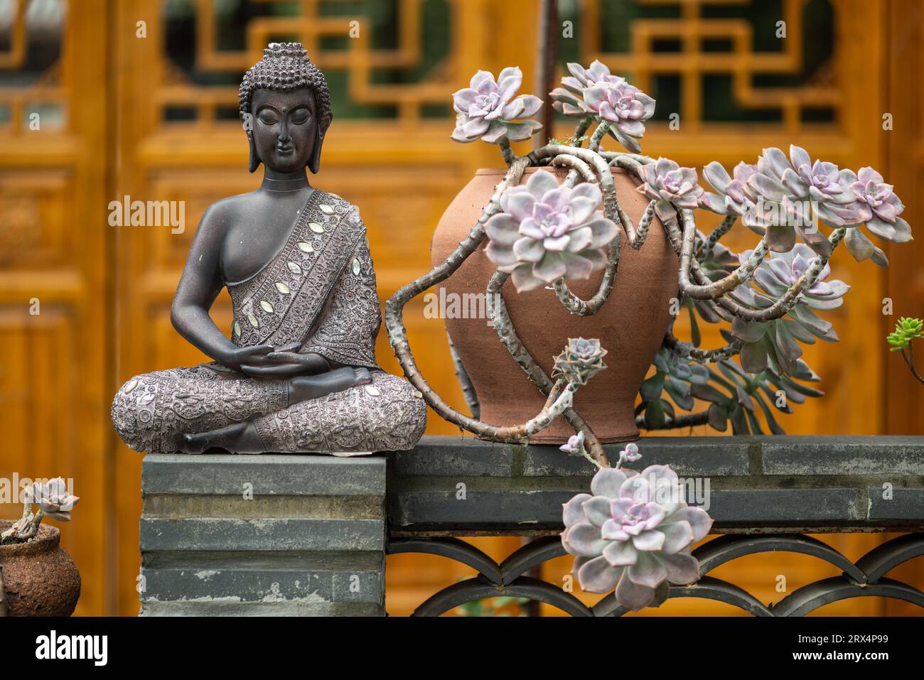 Statua di bronzo del buddha contro la facciata del tempio Foto Stock