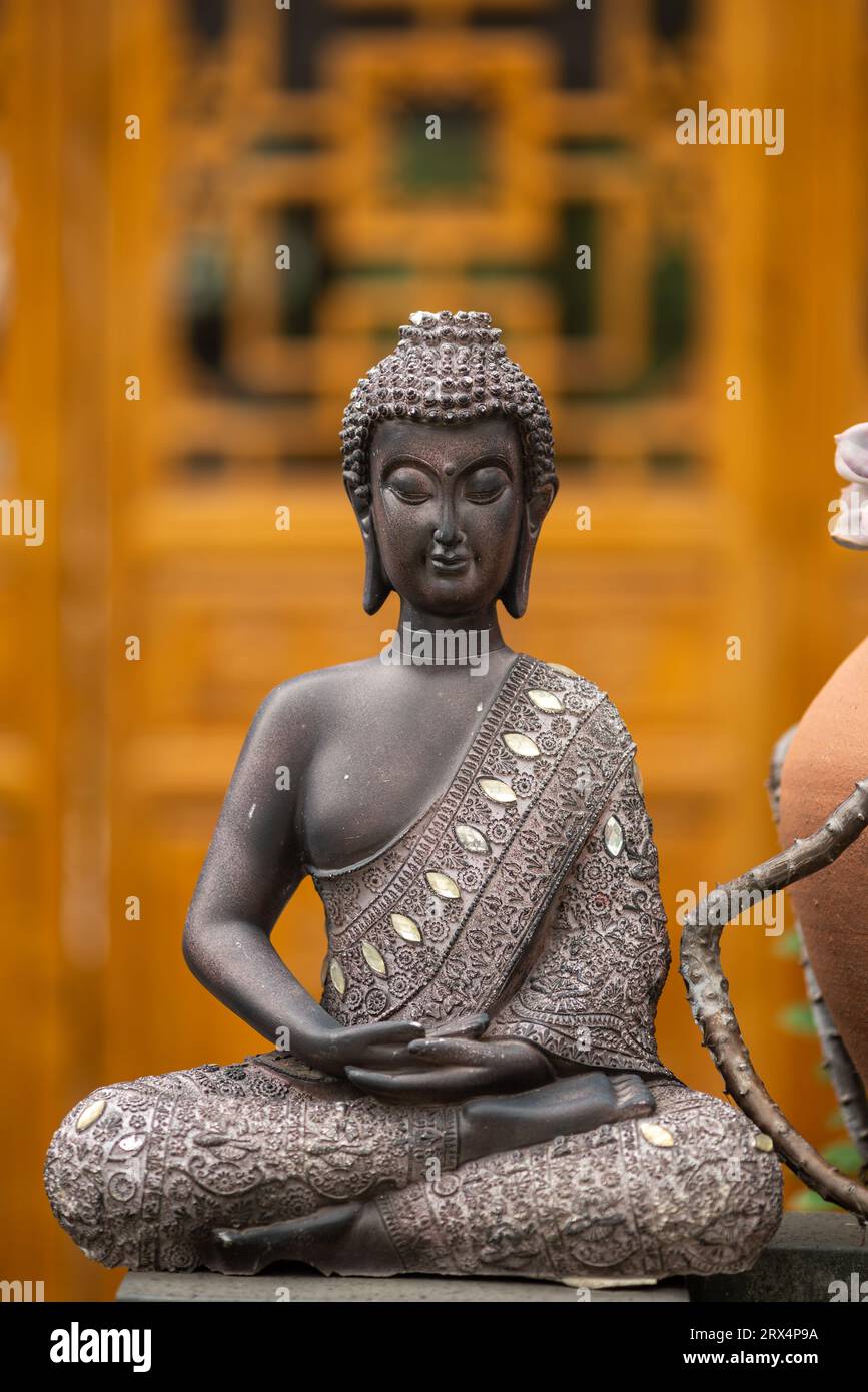 Statua di bronzo del buddha contro la facciata del tempio Foto Stock