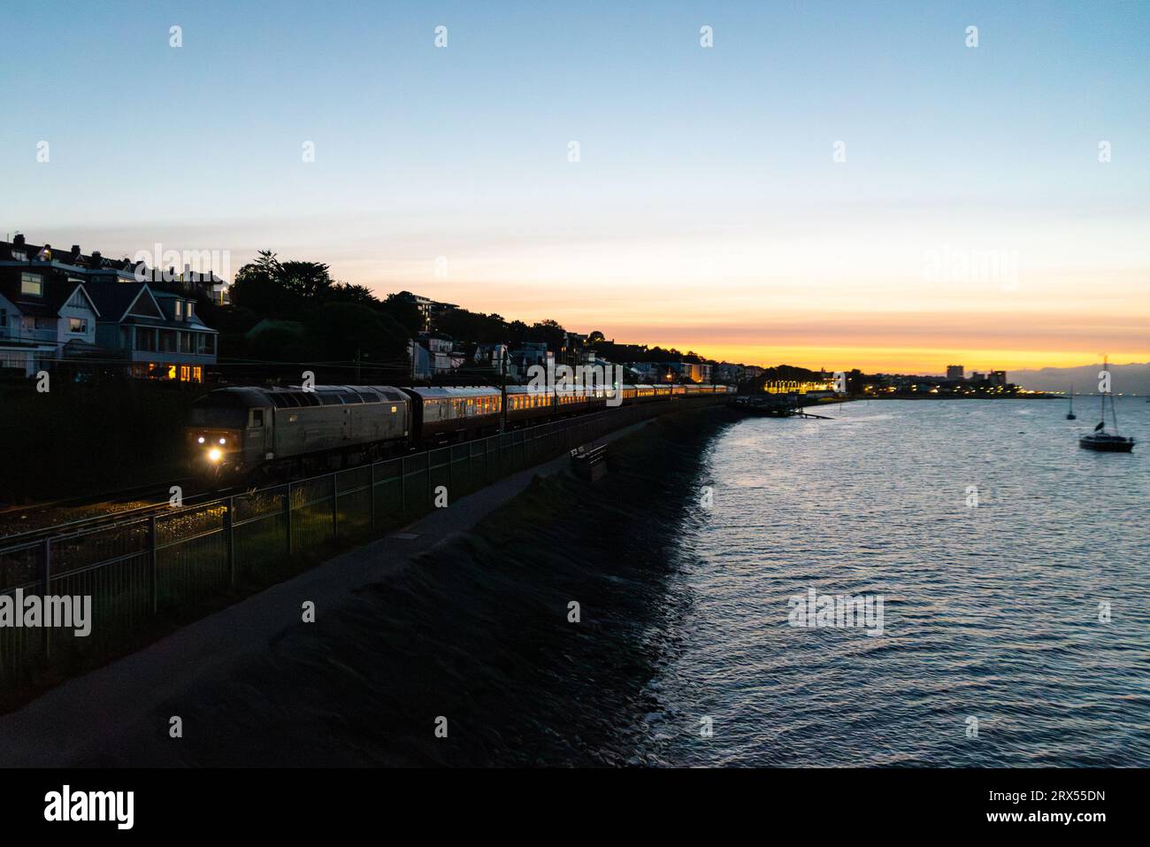 Chalkwell, Southend on Sea, Essex, Regno Unito. 23 settembre 2023. La compagnia di escursioni in treno Steam Dreams sta conducendo un treno speciale da Shoeburyness a York, che è partito trainato da un diesel vintage classe 47 numero D1935. Il tour sold-out ha raccolto i passeggeri da Southend Central alle 06:00 e viene visto passare da Chalkwell accanto all'estuario del Tamigi appena prima dell'alba, il primo giorno dell'Equinozio d'autunno Foto Stock