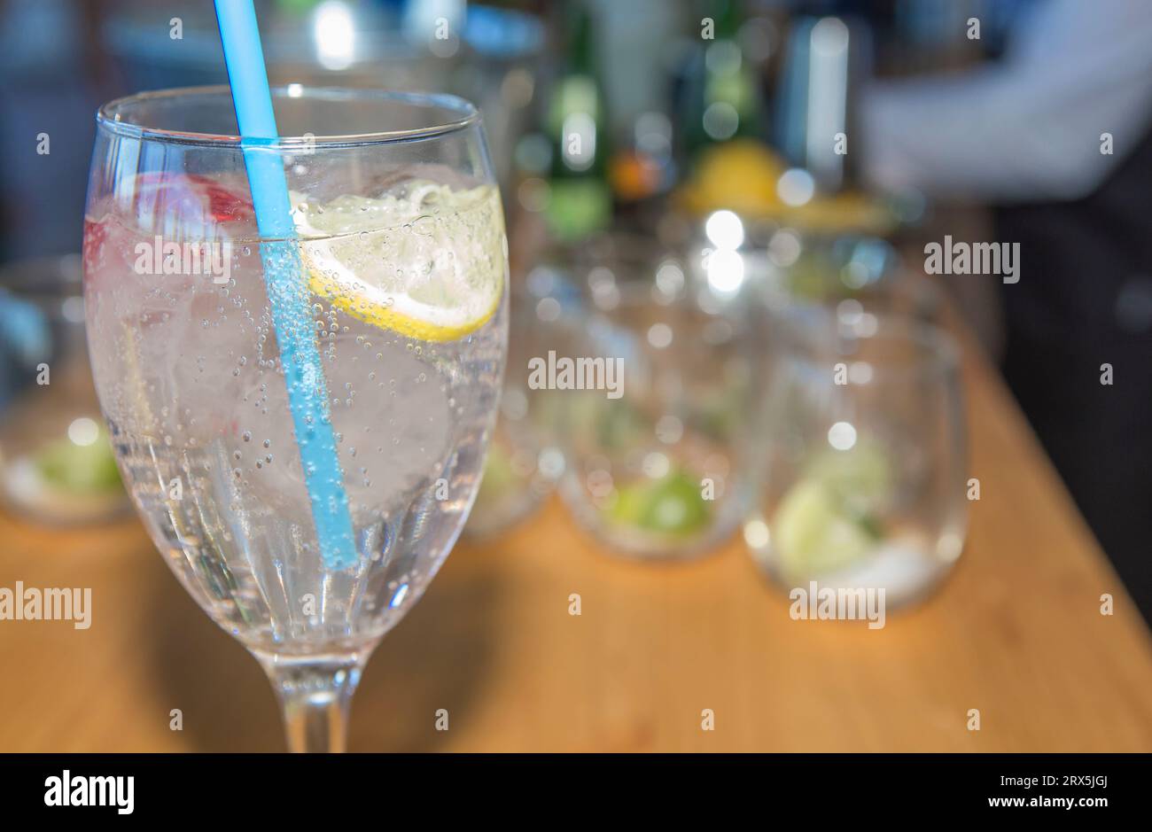 Cocktail rinfrescante con paglia blu. Cameriere che serve cocktail come sottofondo Foto Stock