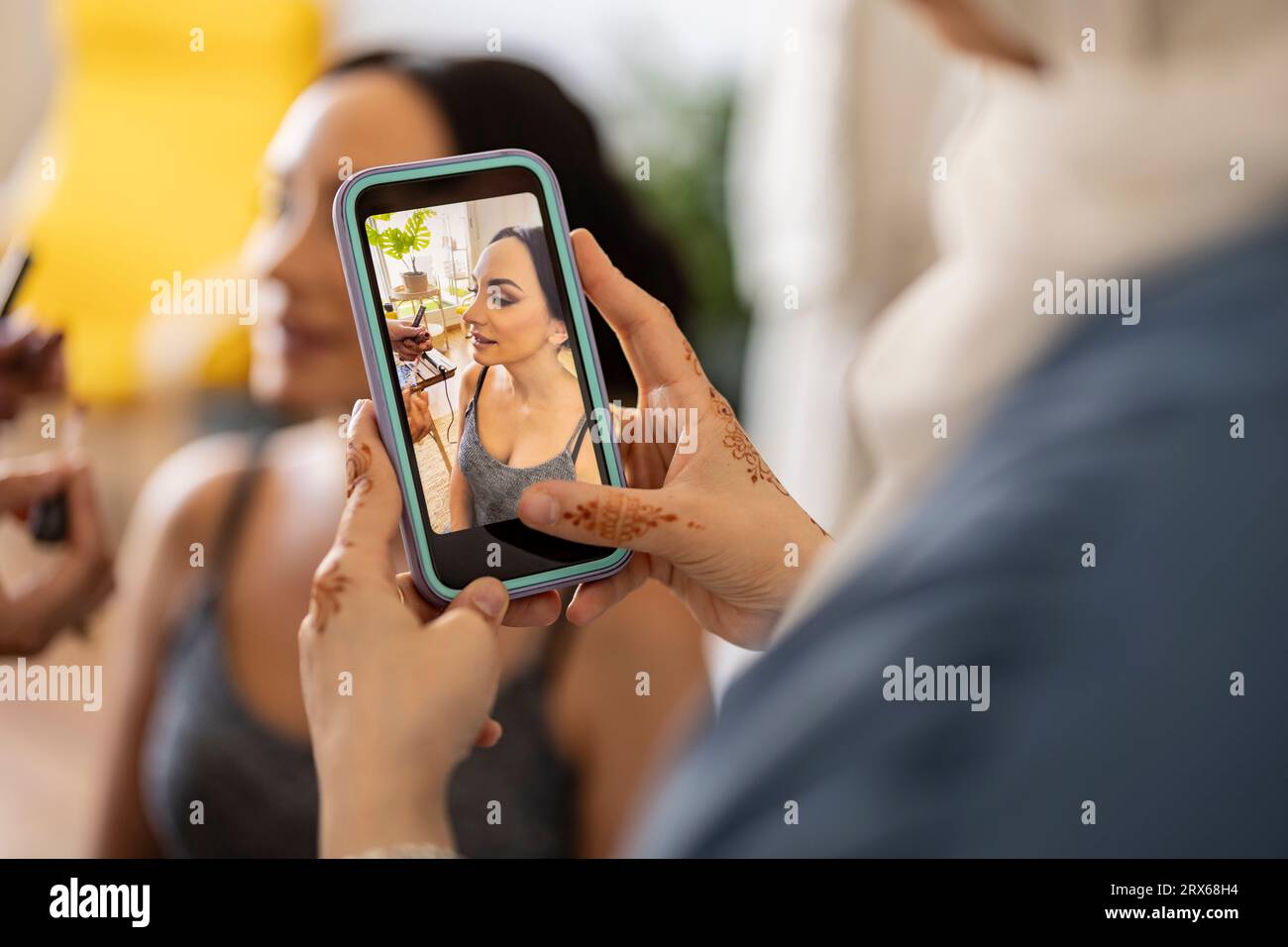 Giovane designer di abiti da sposa che fotografa la sposa tramite smartphone Foto Stock