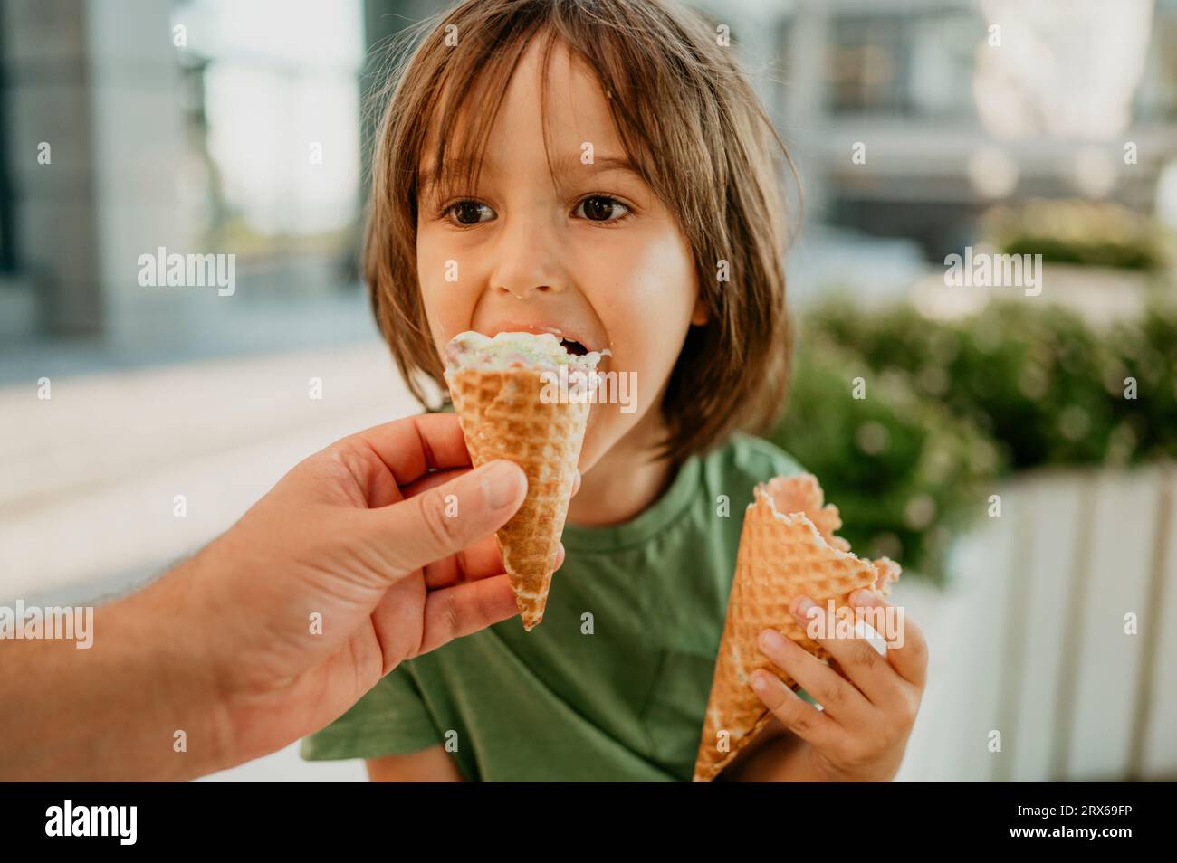 La mano di mio padre dà da mangiare gelato al figlio Foto Stock