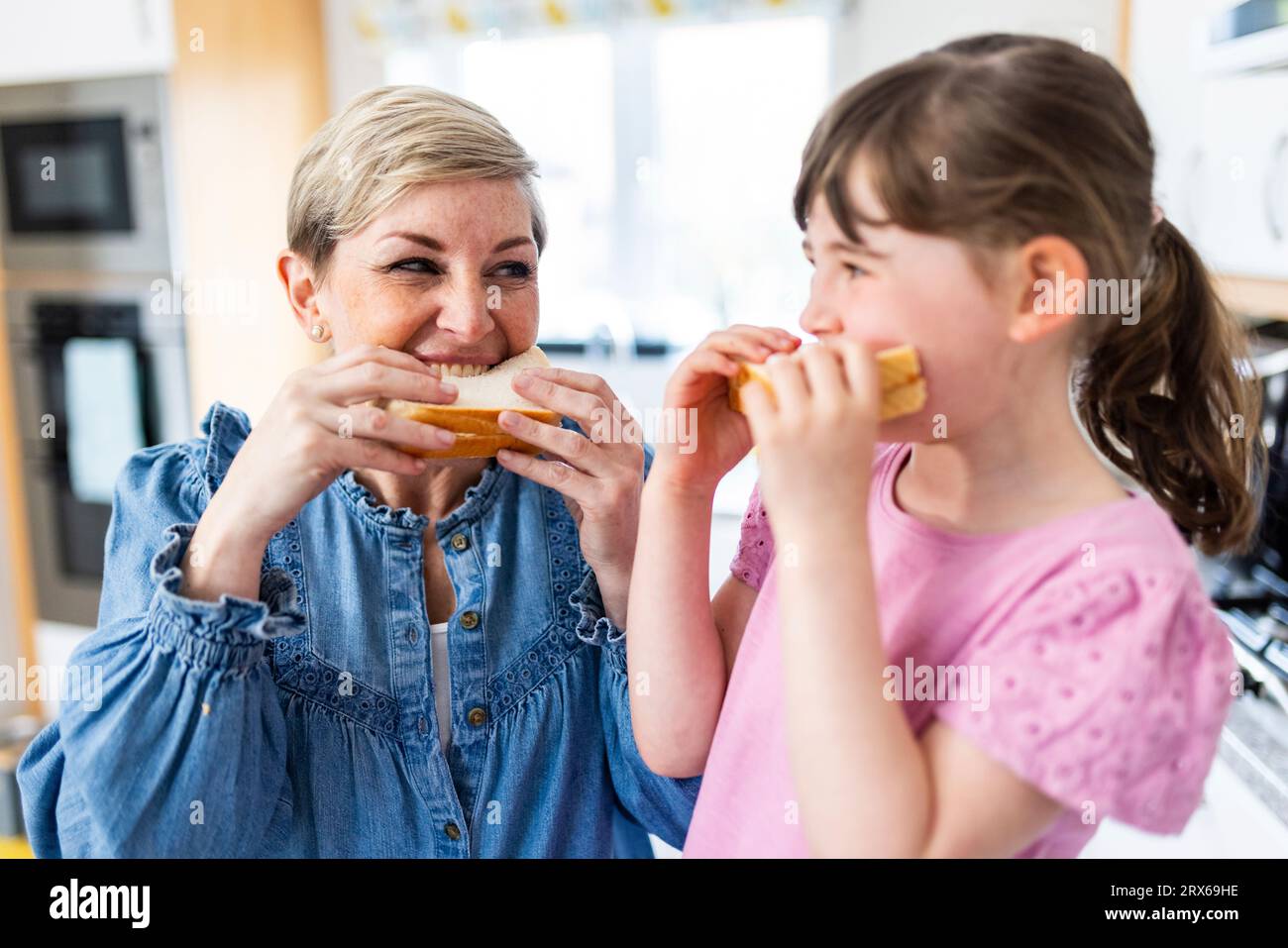 Madre e figlia mangiano panini in cucina Foto Stock