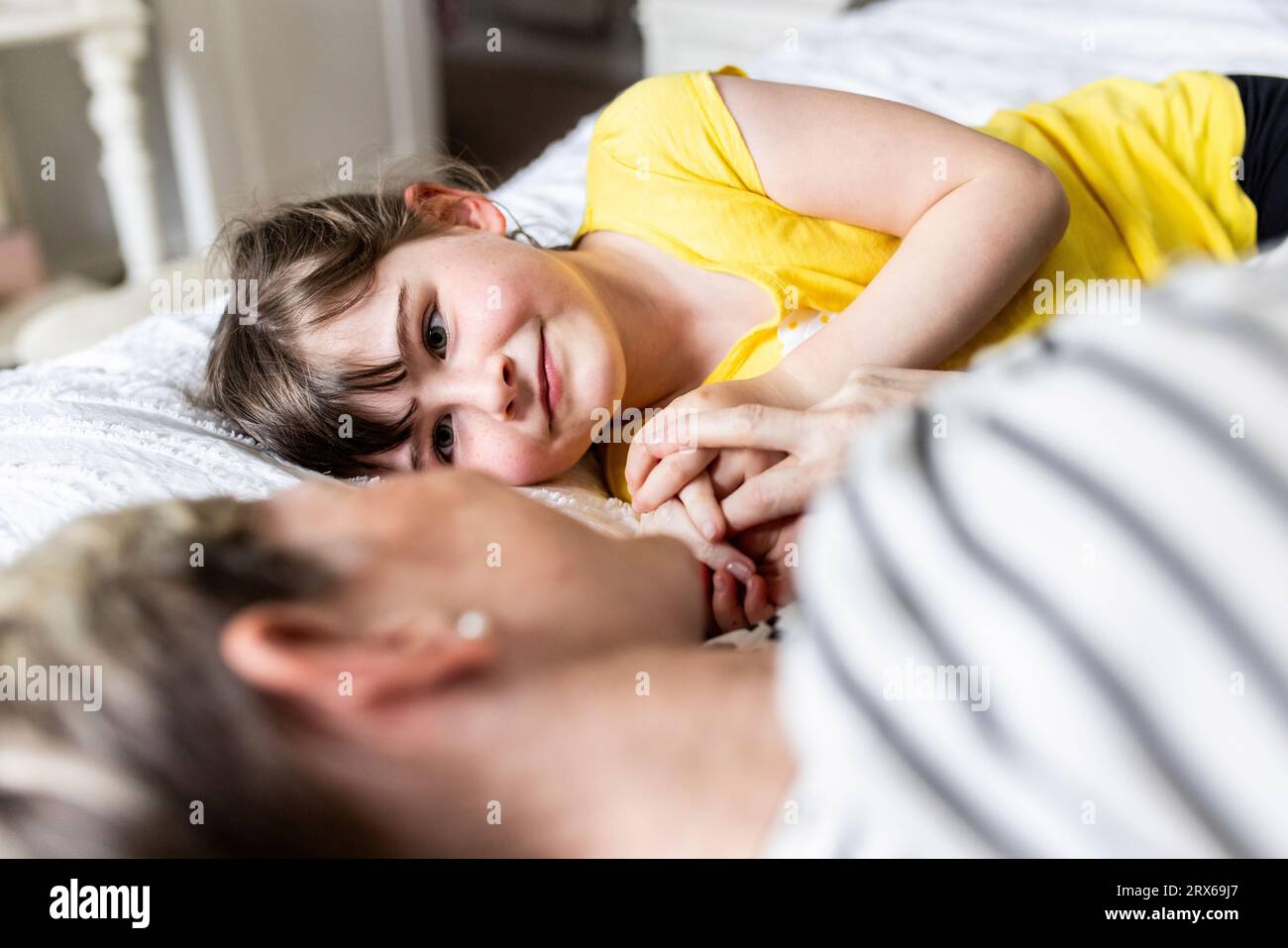 Figlia che riposa con la madre a letto a casa Foto Stock