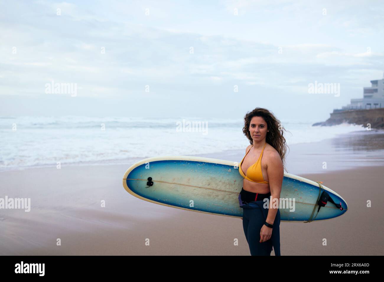 Giovane donna sicura di sé con tavola da surf in spiaggia in vacanza Foto Stock