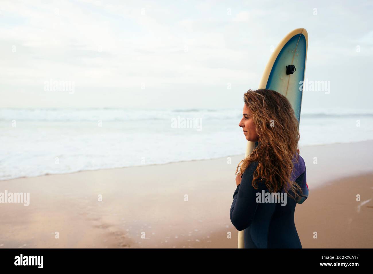 Surfista contemplativo in spiaggia in vacanza Foto Stock