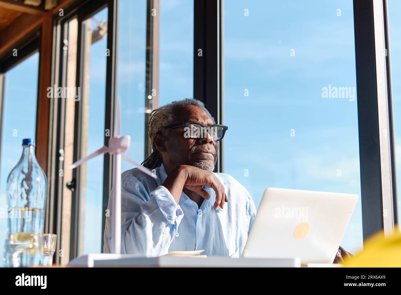 Ingegnere contemplativo seduto al ristorante con un computer portatile Foto Stock