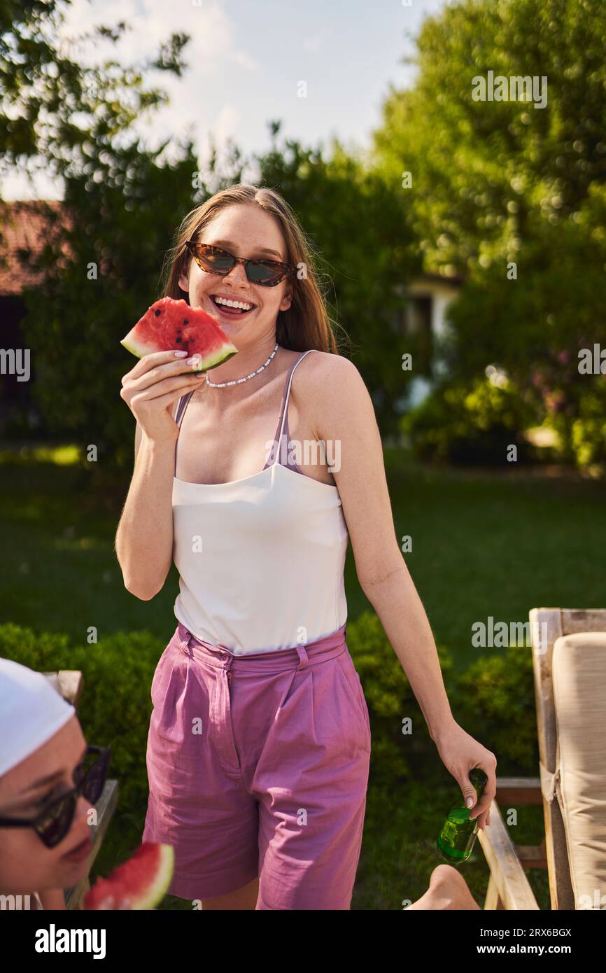 Donna felice che tiene una fetta di anguria nelle giornate di sole Foto Stock