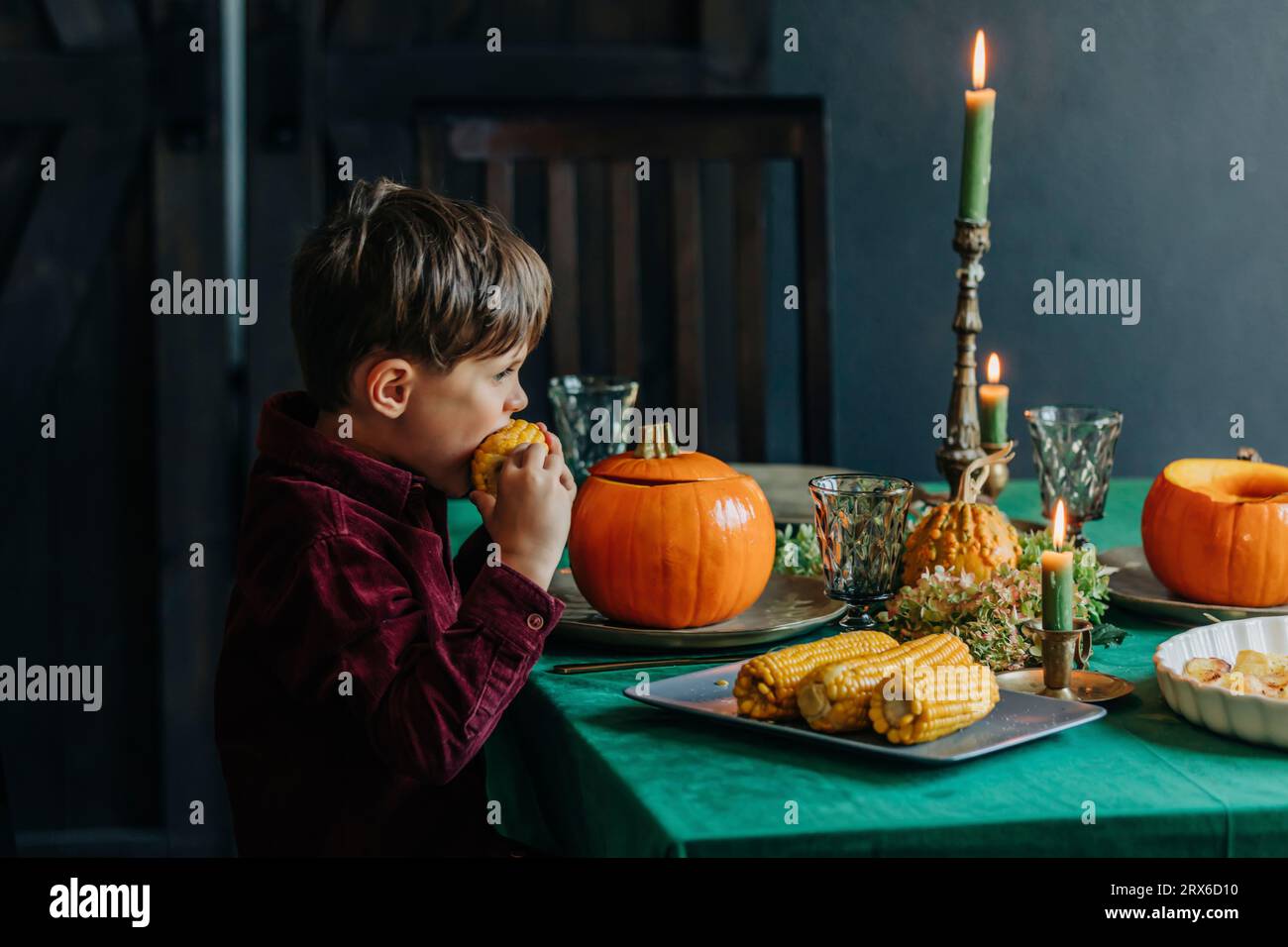 Ragazzo che mangia mais dolce al tavolo da pranzo Foto Stock