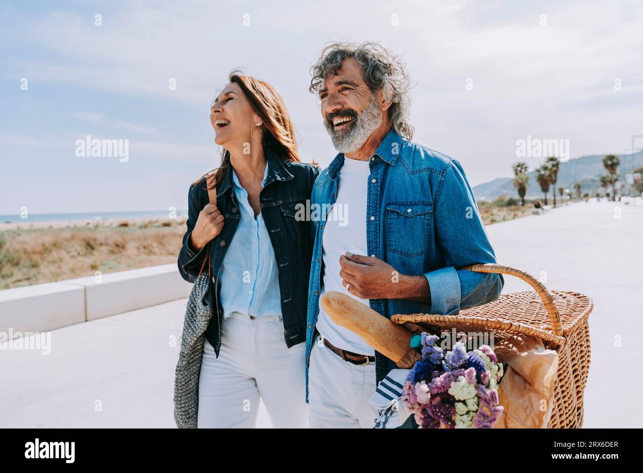 Felice coppia anziana con cestino da picnic vicino alla spiaggia nelle giornate di sole Foto Stock