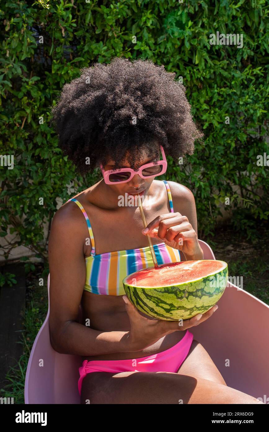 Giovane donna che beve succo d'anguria con cannuccia nelle giornate di sole Foto Stock