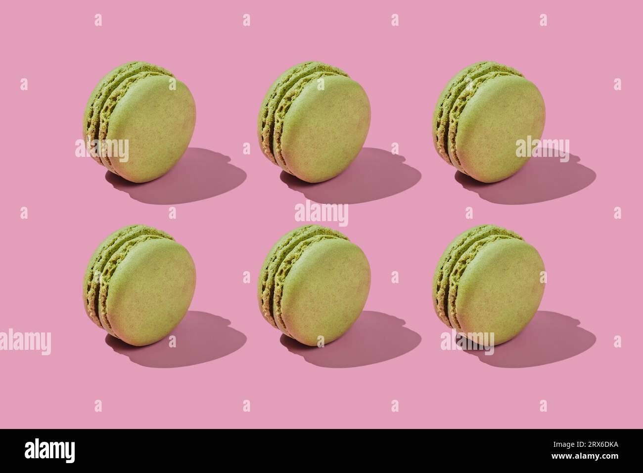 Macaron verdi disposti su sfondo rosa Foto Stock