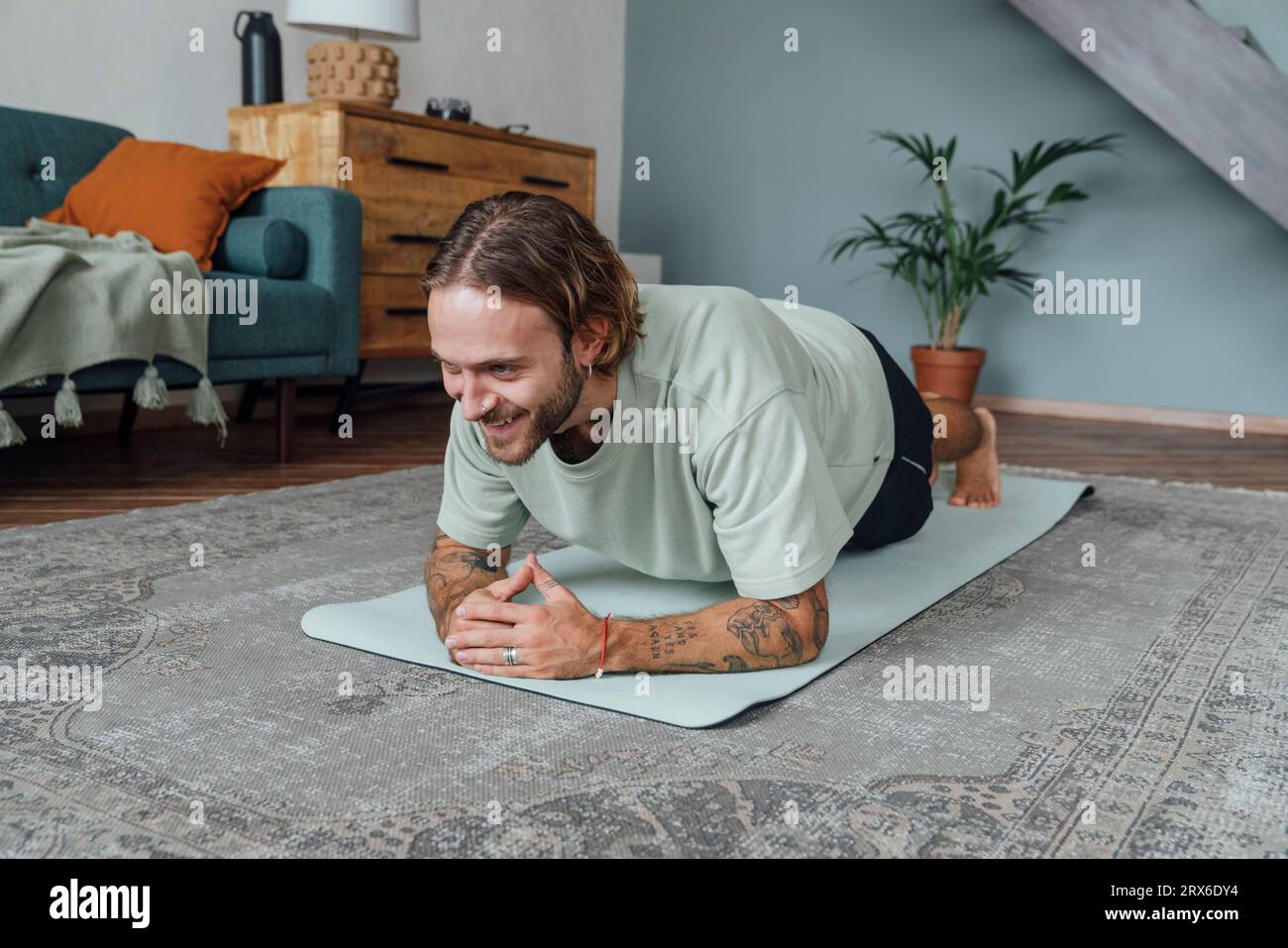 Giovane uomo felice che pratica yoga a casa Foto Stock